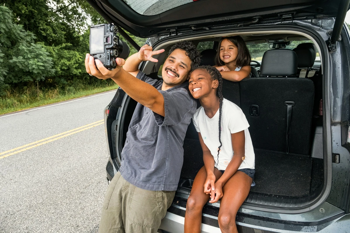 Keluarga berfoto di bagasi mobil; foto stok